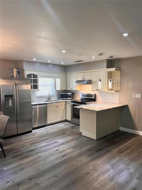 A kitchen features stainless steel appliances, light-colored cabinets, granite countertops, and wood-look flooring — 548 E CHURCH AVENUE, LONGWOOD, FL