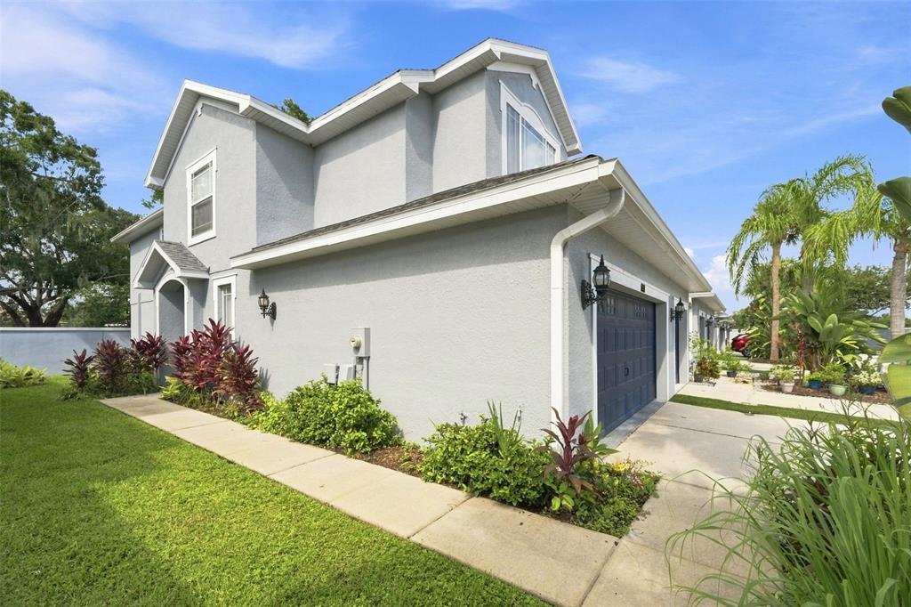A two-story gray house with a garage and a sidewalk surrounded by tropical landscaping — 6030 PARKSIDE MEADOW DRIVE, TAMPA, FL