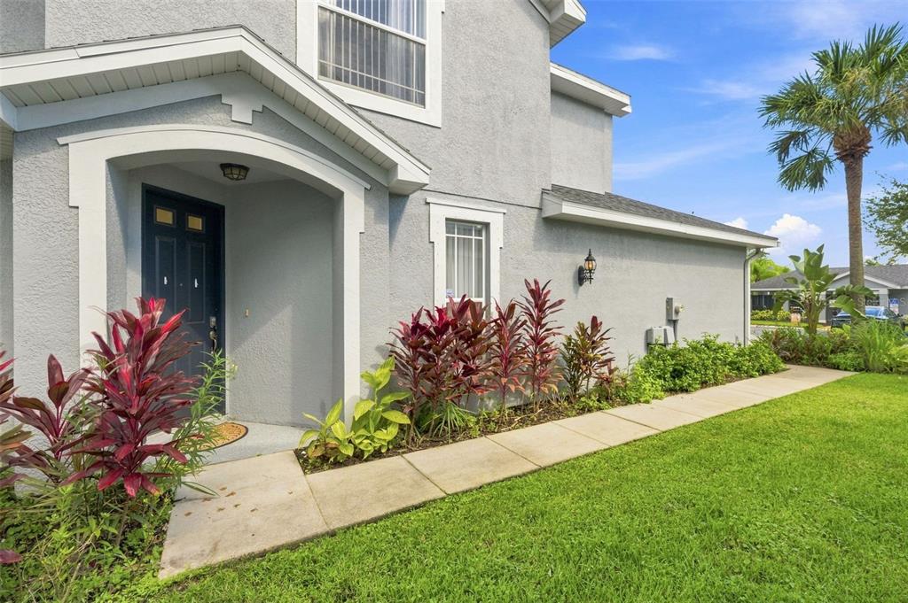 The exterior of a gray two-story house features a covered entryway and a concrete walkway — 6030 PARKSIDE MEADOW DRIVE, TAMPA, FL