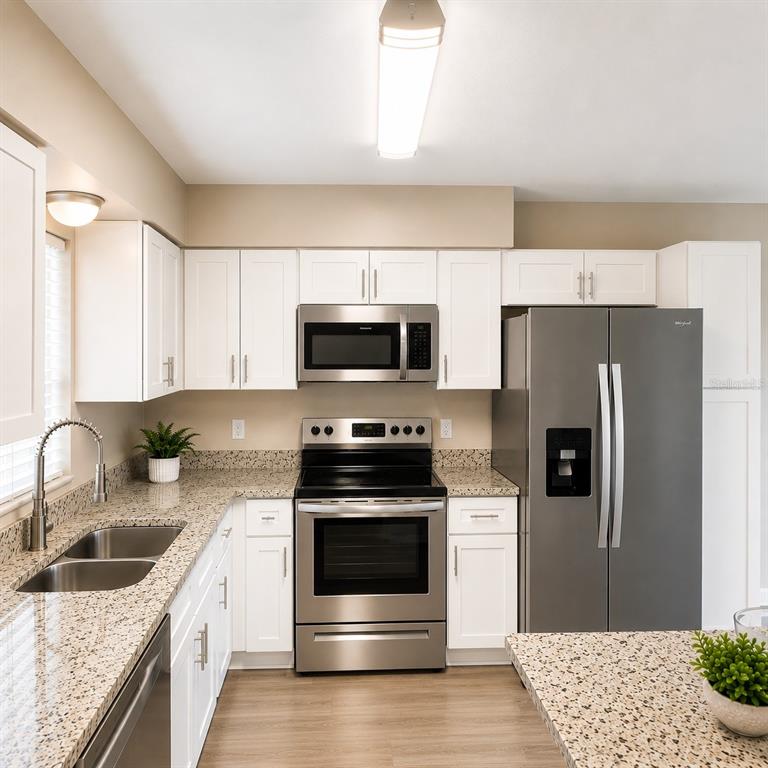 A kitchen features white cabinets, stainless steel appliances, and speckled granite countertops — 1427 BENWICK WAY, CASSELBERRY, FL