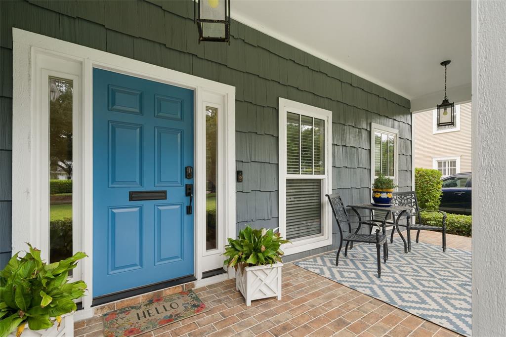 A covered front porch features a blue door, gray shingle siding, and a small bistro set — 3233 W PARKLAND BOULEVARD, TAMPA, FL