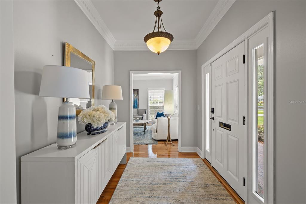 A bright entryway features a white console table, a patterned rug, and a hanging pendant light — 3233 W PARKLAND BOULEVARD, TAMPA, FL