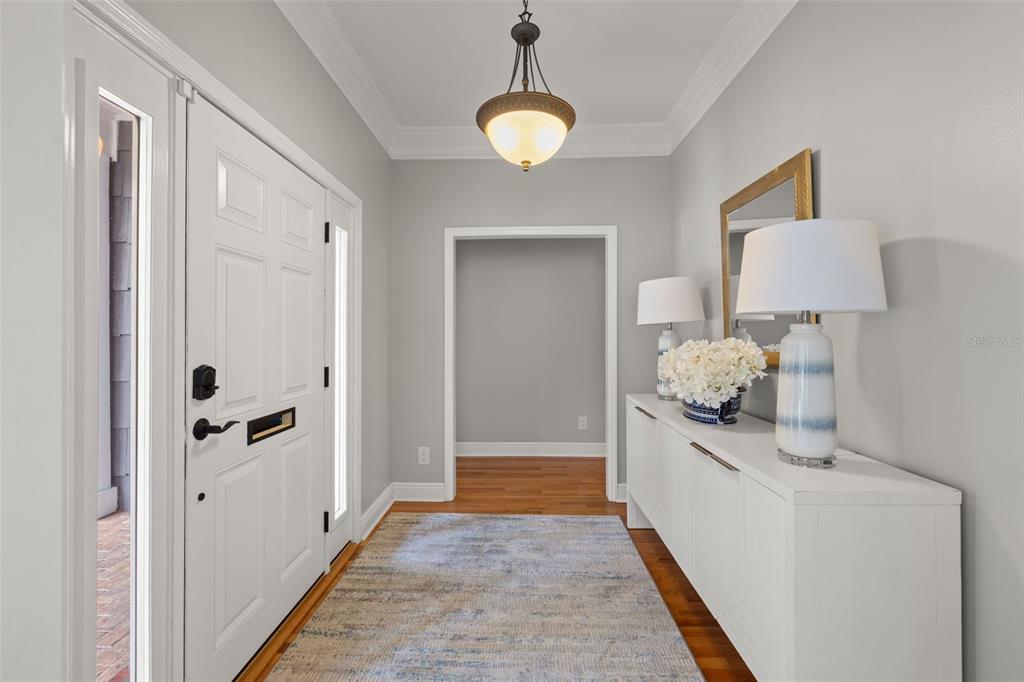 A bright entryway features a white door, hardwood floors, a rug, and a console table — 3233 W PARKLAND BOULEVARD, TAMPA, FL