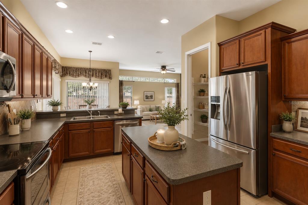 A spacious living room features tan tile flooring, yellow walls, a ceiling fan, and sliding doors — 16407 BRISTOL LAKE CIRCLE, ORLANDO, FL