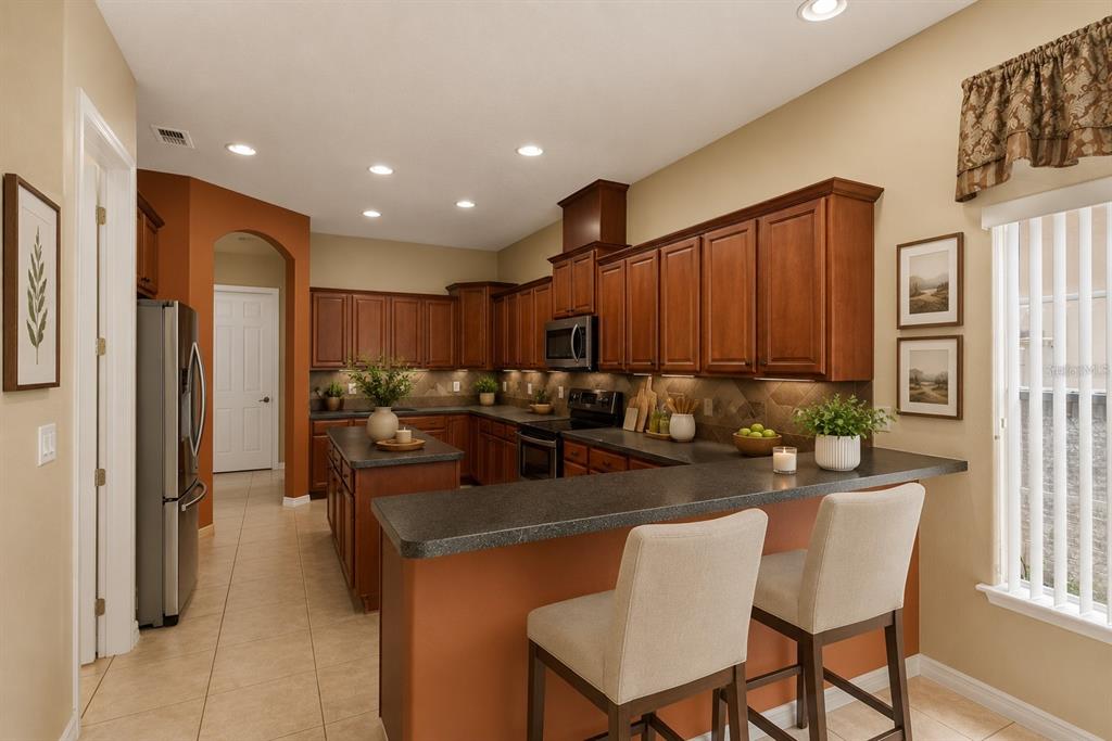 A kitchen with wood cabinets, stainless steel appliances, a central island, and tile flooring — 16407 BRISTOL LAKE CIRCLE, ORLANDO, FL