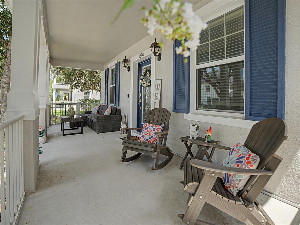 A covered front porch features two wooden rocking chairs, a sofa, and blue shutters — 16910 DORMAN ROAD, LITHIA, FL