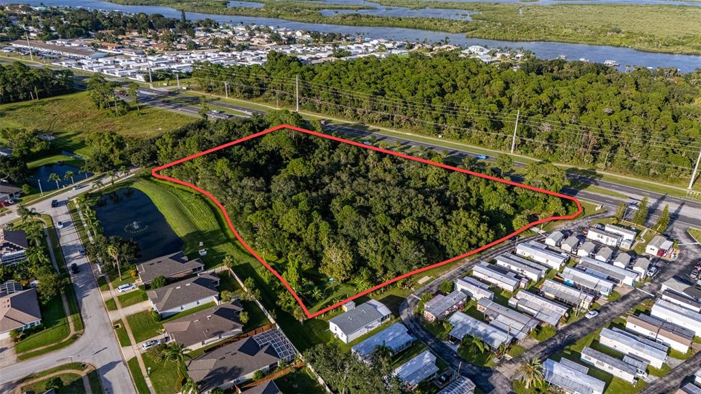 An aerial view shows a wooded lot outlined in red next to a residential neighborhood — 2370 S RIDGEWOOD AVENUE, EDGEWATER, FL