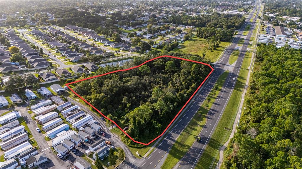 An aerial view shows a wooded, triangular plot of land outlined in red near a highway — 2370 S RIDGEWOOD AVENUE, EDGEWATER, FL