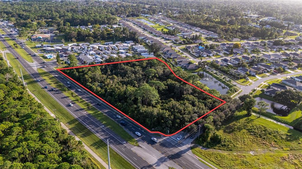 An aerial view shows a vacant, wooded lot outlined in red next to a highway — 2370 S RIDGEWOOD AVENUE, EDGEWATER, FL