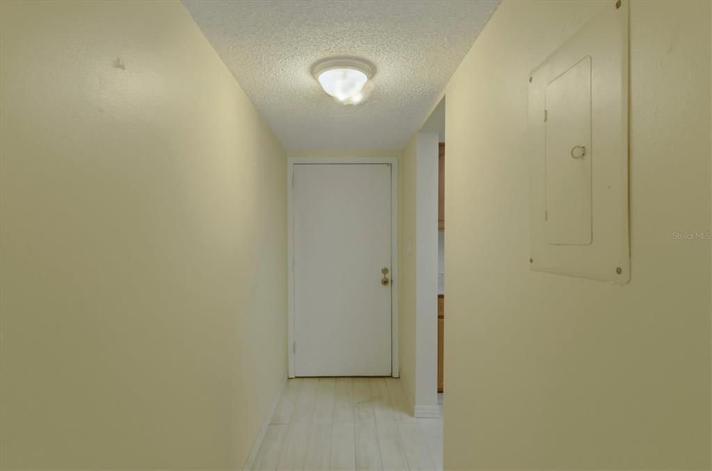 A hallway with light yellow walls, a white door, and a ceiling light fixture — 4143 HERON WAY 207 BLDG E, BRADENTON, FL