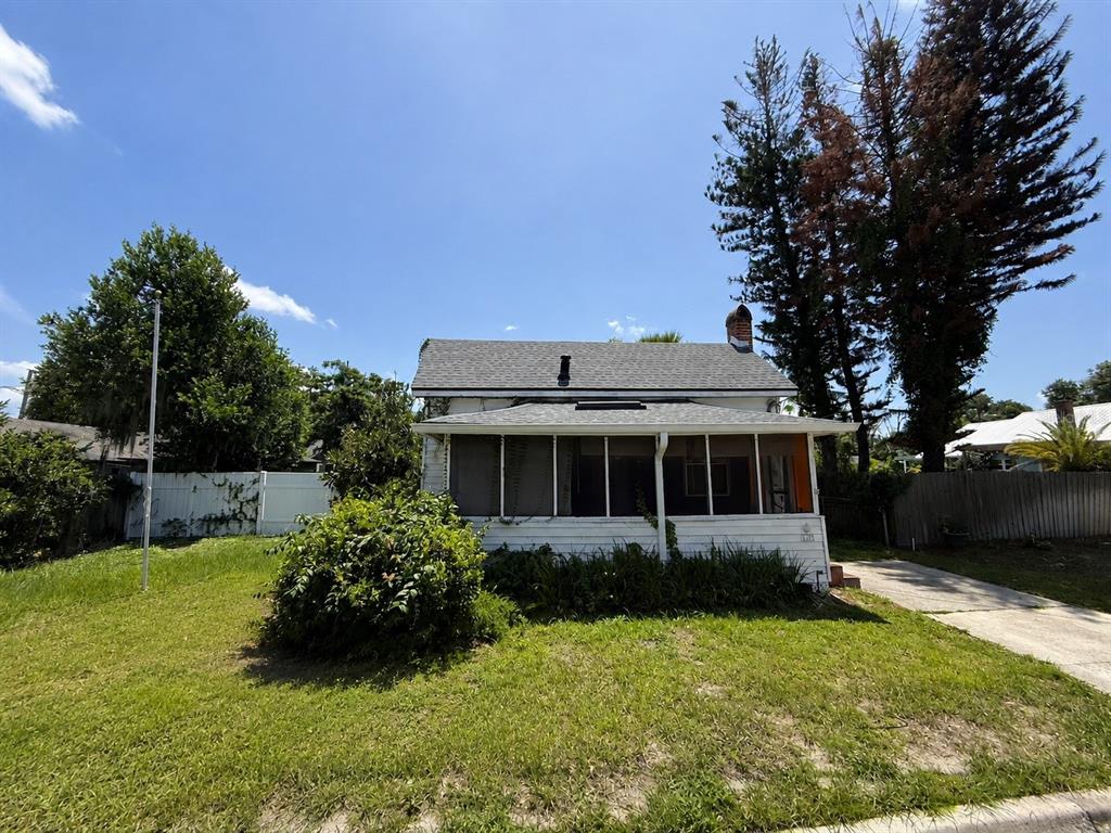 A white house with a screened-in front porch stands on a grassy lot with trees — 1101 N HAMPTON AVENUE, ORLANDO, FL