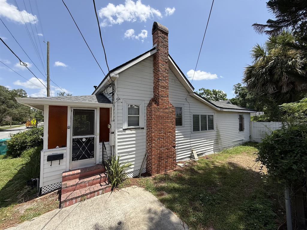 A white house with a brick chimney and a small front porch under a blue sky — 1101 N HAMPTON AVENUE, ORLANDO, FL
