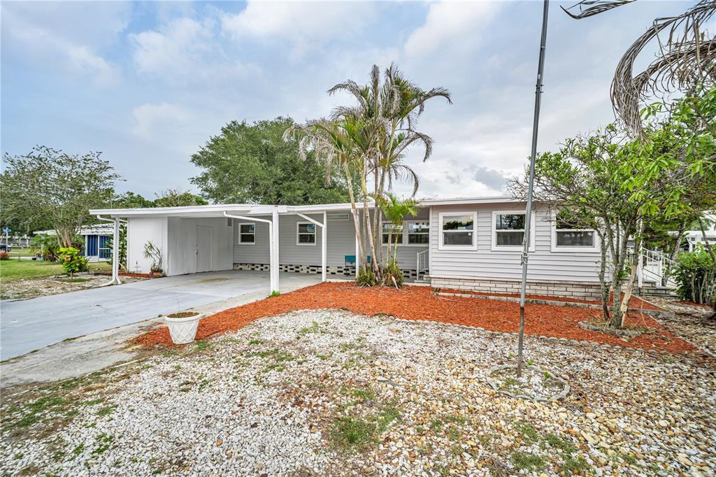 A single-story house with light gray siding, a carport, and a gravel front yard — 193 BLUE MARLIN DRIVE, OLDSMAR, FL