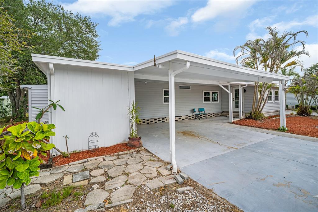A light gray house features a concrete carport, a stone walkway, and a palm tree — 193 BLUE MARLIN DRIVE, OLDSMAR, FL