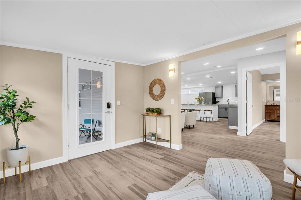 A bright entryway with wood-look flooring leads into an open-concept kitchen and living area — 193 BLUE MARLIN DRIVE, OLDSMAR, FL