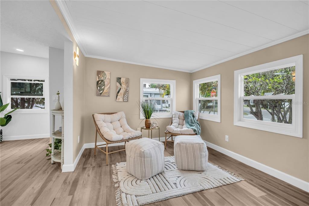A sunlit living room features light wood flooring, two wicker chairs, and two fabric ottomans — 193 BLUE MARLIN DRIVE, OLDSMAR, FL