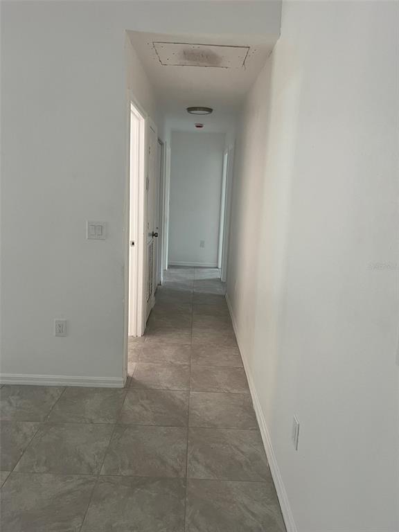 A hallway with light gray tile flooring leads toward a doorway at the far end — 3422 NW 26TH AVENUE, OKEECHOBEE, FL