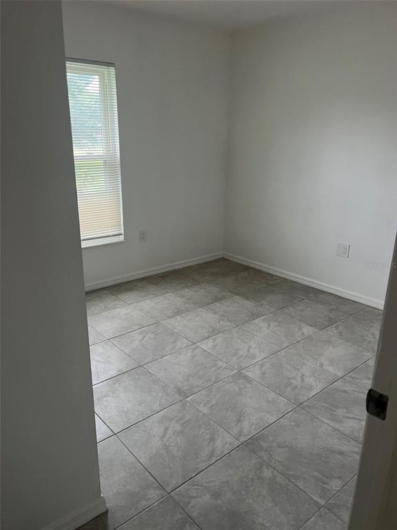 An empty room with light gray tile flooring, white walls, and a single window — 3422 NW 26TH AVENUE, OKEECHOBEE, FL