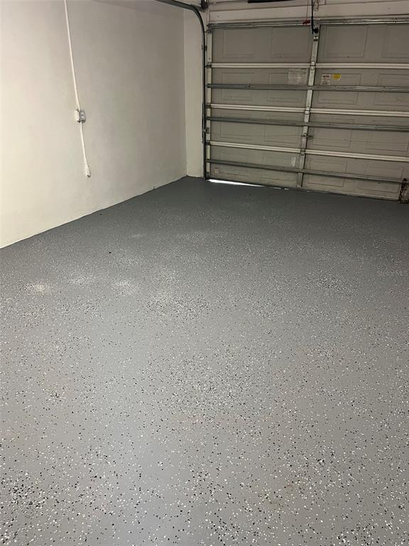 A garage interior featuring a gray epoxy floor with decorative white and black paint flecks — 3422 NW 26TH AVENUE, OKEECHOBEE, FL