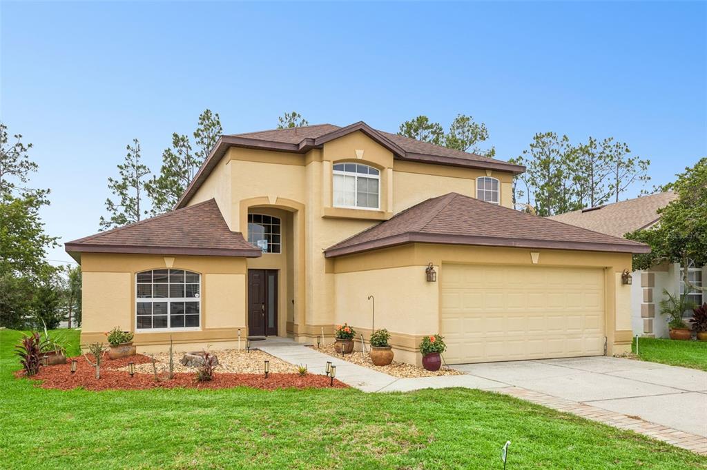 A two-story tan stucco house with a brown shingled roof and a two-car garage — 726 OXFORD DRIVE, DAVENPORT, FL