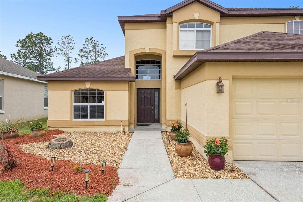 The exterior of a two-story tan house features a brown roof, garage, and front walkway — 726 OXFORD DRIVE, DAVENPORT, FL