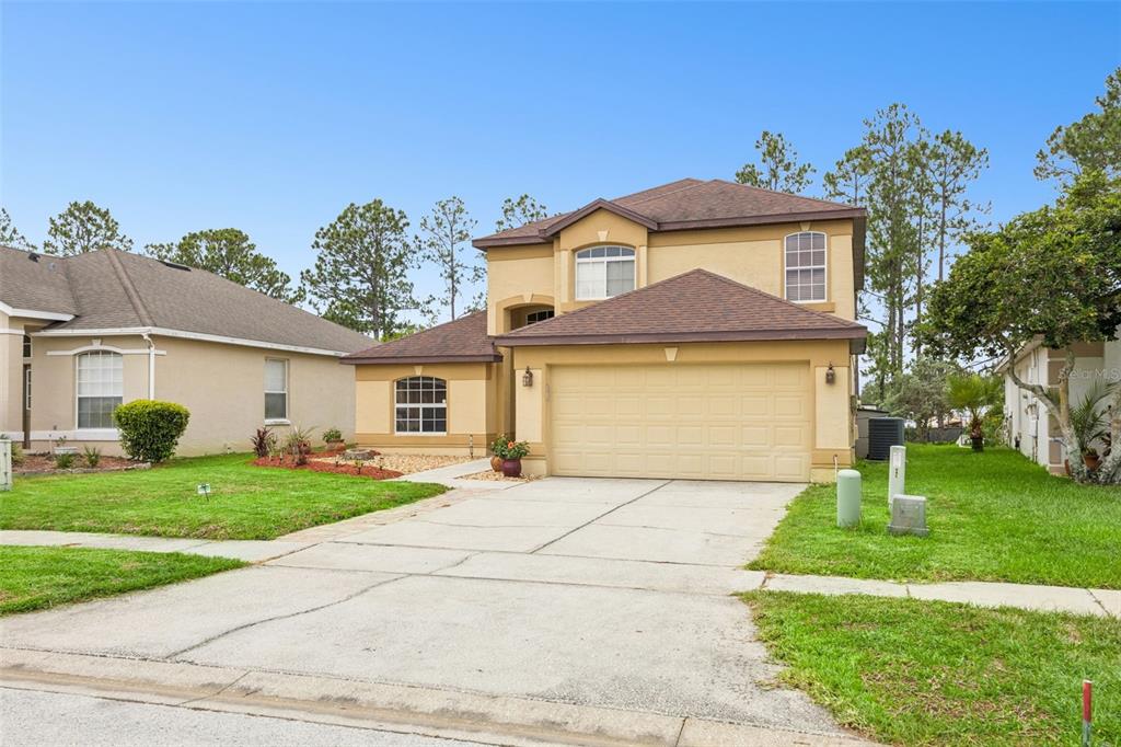 A two-story suburban house with a tan stucco exterior, brown shingled roof, and attached garage — 726 OXFORD DRIVE, DAVENPORT, FL