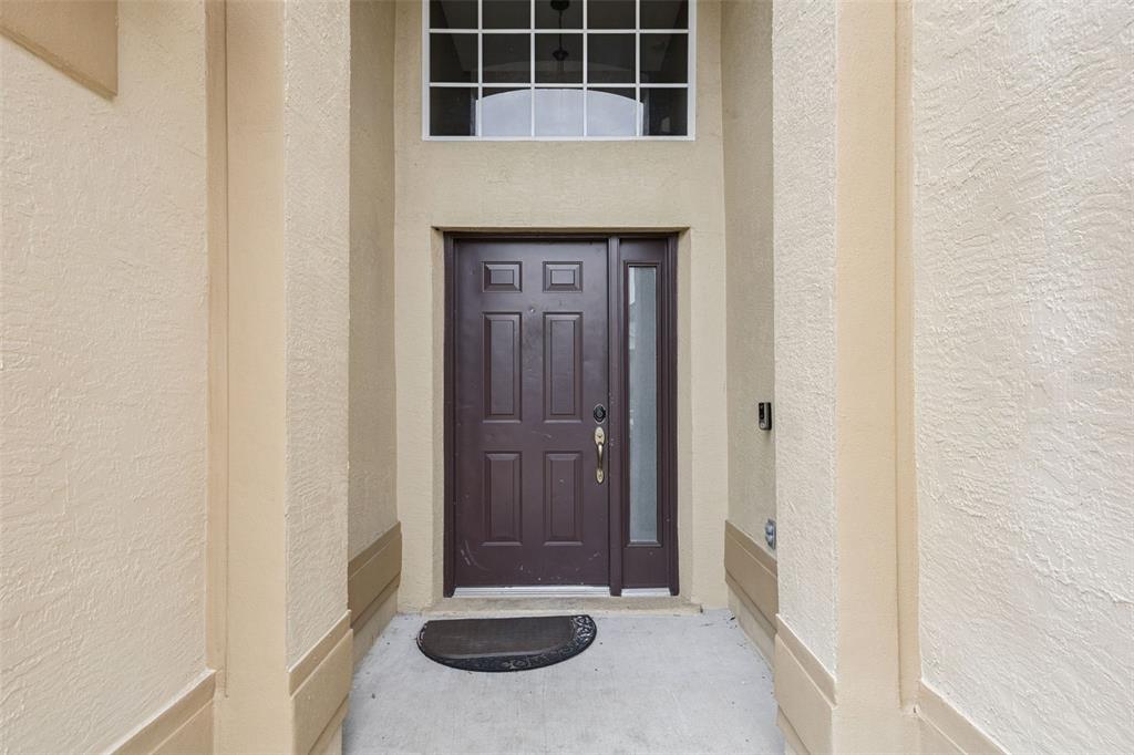 A dark brown front door with a side light sits within a recessed entryway — 726 OXFORD DRIVE, DAVENPORT, FL