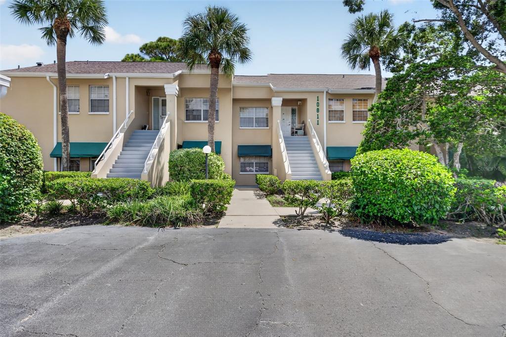 A two-story tan apartment building features two exterior staircases and green awnings over the windows — 10811 INDIAN HILLS COURT UNIT 37, SEMINOLE, FL