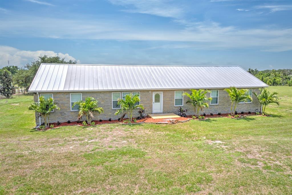 A single-story stone house with a metal roof sits on a grassy lot — 325 STENSTROM ROAD, WAUCHULA, FL