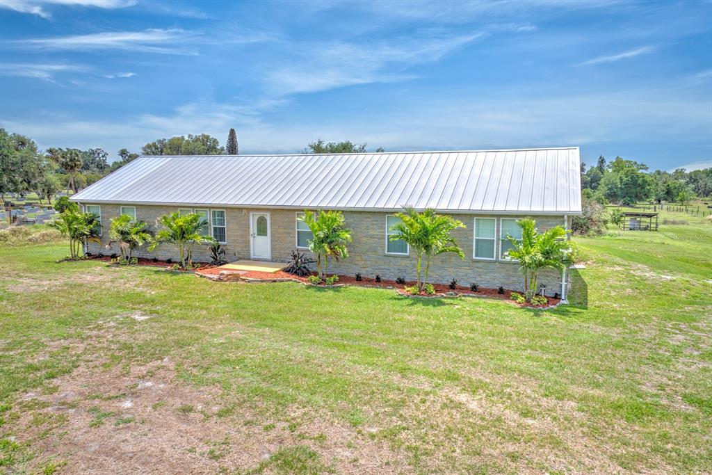 A single-story house with a stone facade and a metal roof sits on a grassy lot — 325 STENSTROM ROAD, WAUCHULA, FL