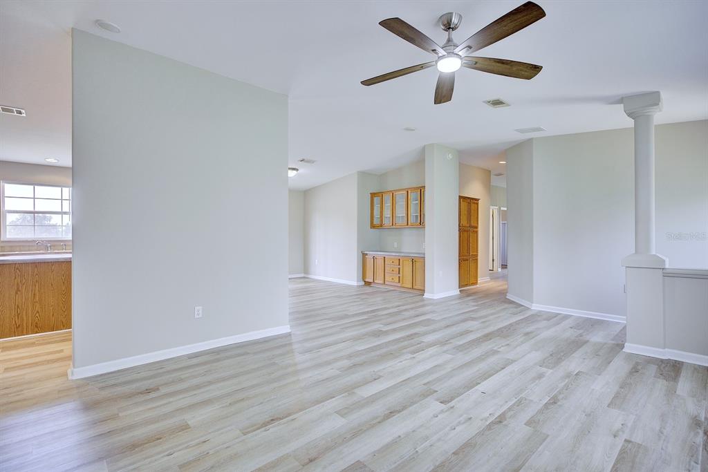An open-concept living area features light wood-look flooring, a ceiling fan, and wooden cabinetry — 325 STENSTROM ROAD, WAUCHULA, FL