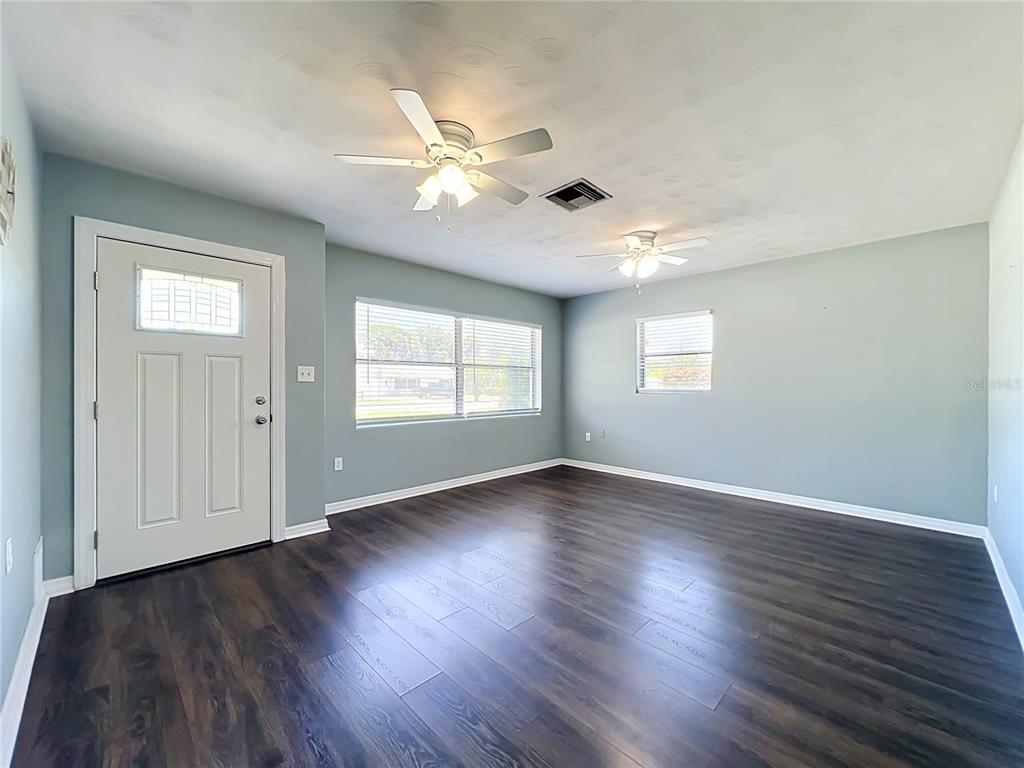 An empty room features light blue walls, dark wood-look flooring, and two ceiling fans — 2980 WESTLAND ROAD, MOUNT DORA, FL