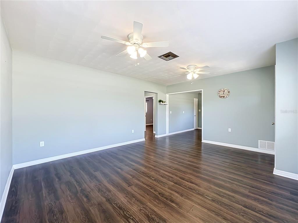 An empty room with light blue walls, dark wood-look flooring, and two ceiling fans — 2980 WESTLAND ROAD, MOUNT DORA, FL