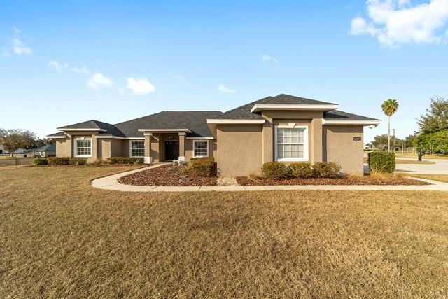 A tan, single-story suburban house with a dark roof stands under a sunset sky — 3305 NE 106TH STREET, ANTHONY, FL