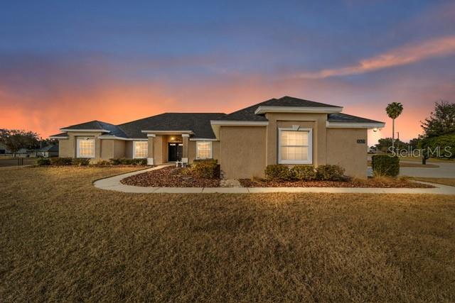A tan, single-story stucco house with a dark shingled roof and a dry grass lawn — 3305 NE 106TH STREET, ANTHONY, FL