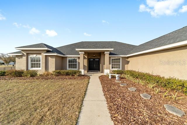 A single-story house with a beige stucco exterior, dark shingle roof, and a concrete walkway — 3305 NE 106TH STREET, ANTHONY, FL