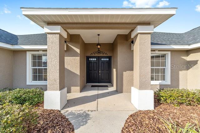 The front entrance of a house features a covered porch with two columns and a dark door — 3305 NE 106TH STREET, ANTHONY, FL