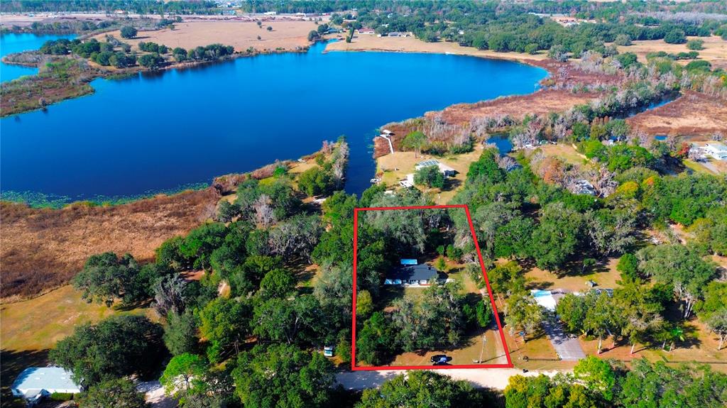 An aerial view shows a house outlined in red situated on a wooded lot near water — 8807 OVERLOOK DRIVE, WESLEY CHAPEL, FL