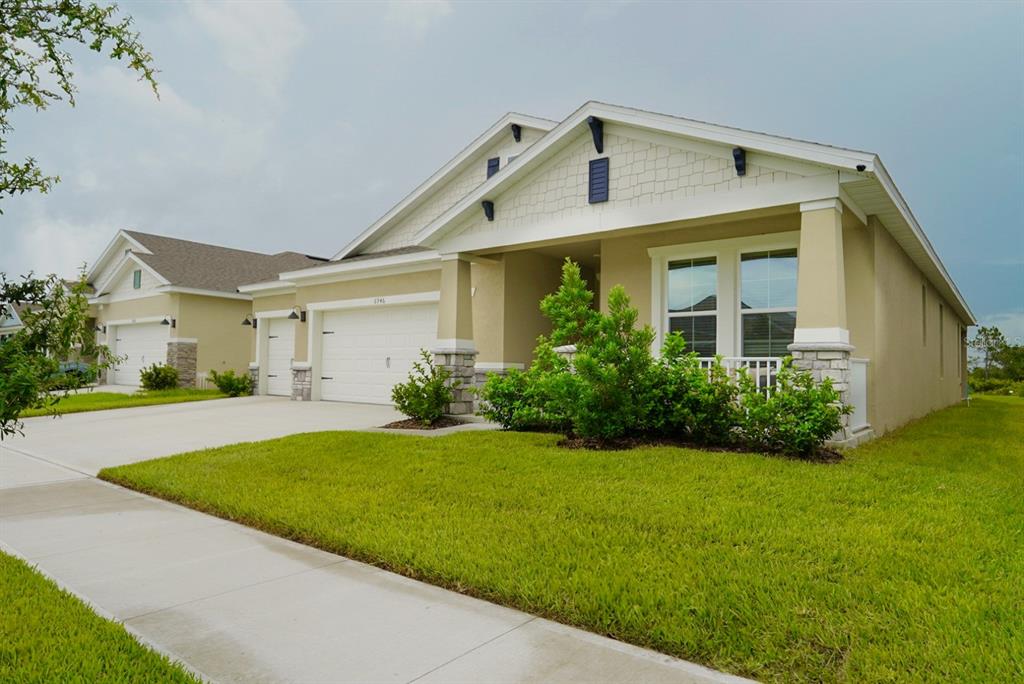 A single-story suburban house with a tan stucco exterior, stone accents, and a two-car garage — 6946 AUDOBON OSPREY COVE, HARMONY, FL