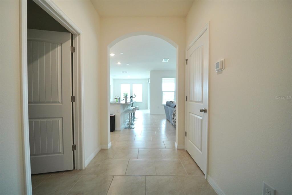 A tiled hallway leads through an arched doorway into an open-concept kitchen and living area — 6946 AUDOBON OSPREY COVE, HARMONY, FL