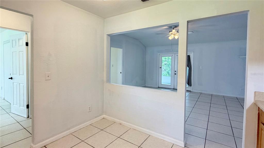 A view from a tiled dining area through a pass-through window into a living room — 601 SOLDIER SQUARE, CASSELBERRY, FL