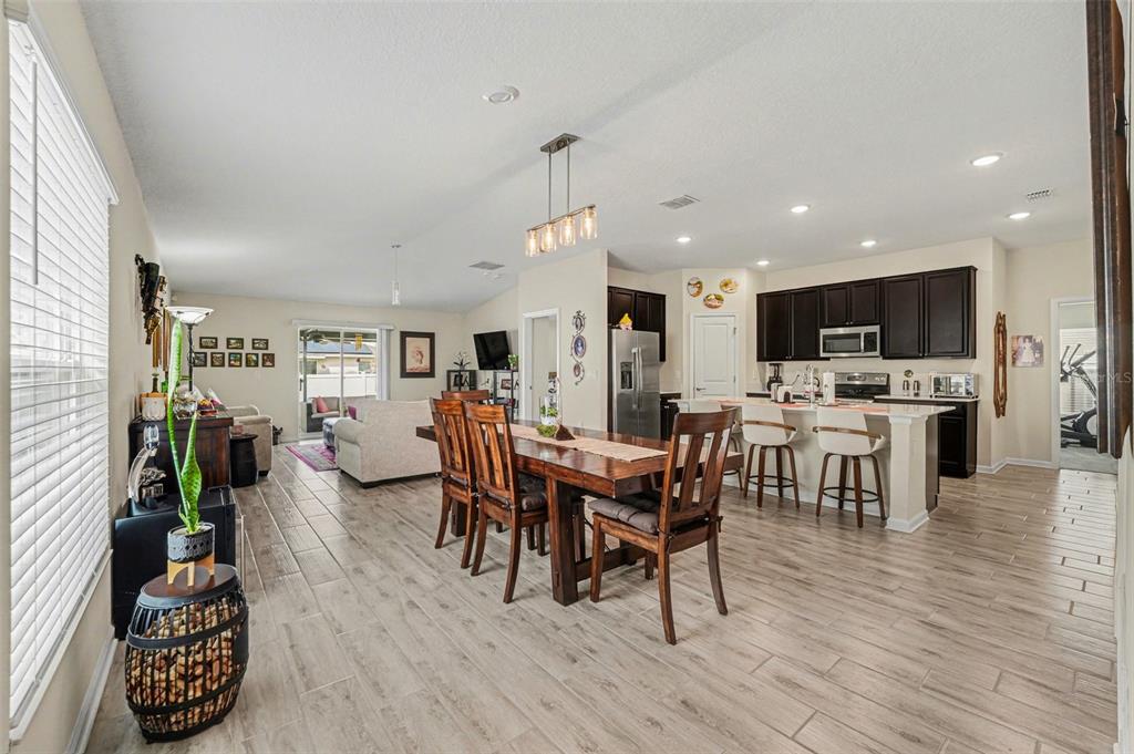 An open-concept dining area and kitchen feature dark wood cabinets and light wood-look flooring — 143 PERSHING STREET, BARTOW, FL