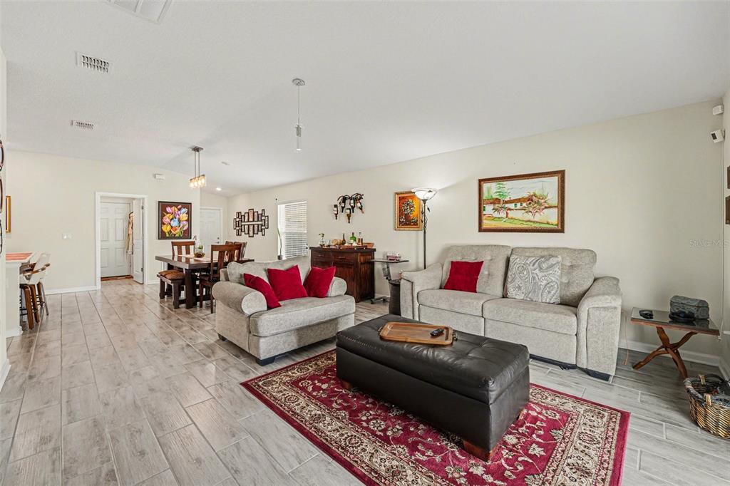 A living room and dining area with light wood-look tile floors and neutral walls — 143 PERSHING STREET, BARTOW, FL