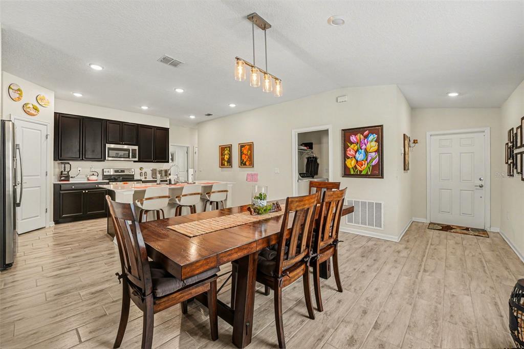 A dining area with a wooden table and chairs sits adjacent to an open kitchen — 143 PERSHING STREET, BARTOW, FL