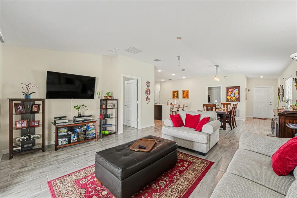 A living room features a television, a leather ottoman, and a dining area in back — 143 PERSHING STREET, BARTOW, FL
