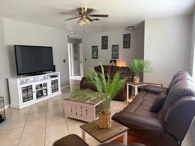 A living room features a television on a white stand, brown sofas, and tile flooring — 914 NICHOLSON ST, CLEARWATER, FL
