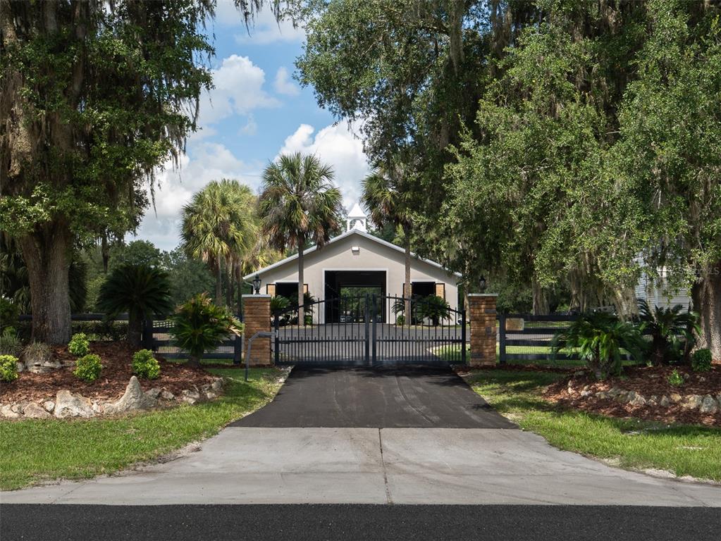 A gated entrance leads to a detached garage building surrounded by trees and landscaping — 3680 NW 115TH AVENUE, OCALA, FL
