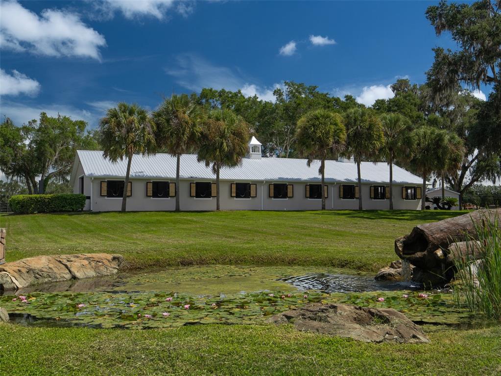 A white barn with a metal roof sits behind a pond with lily pads — 3680 NW 115TH AVENUE, OCALA, FL