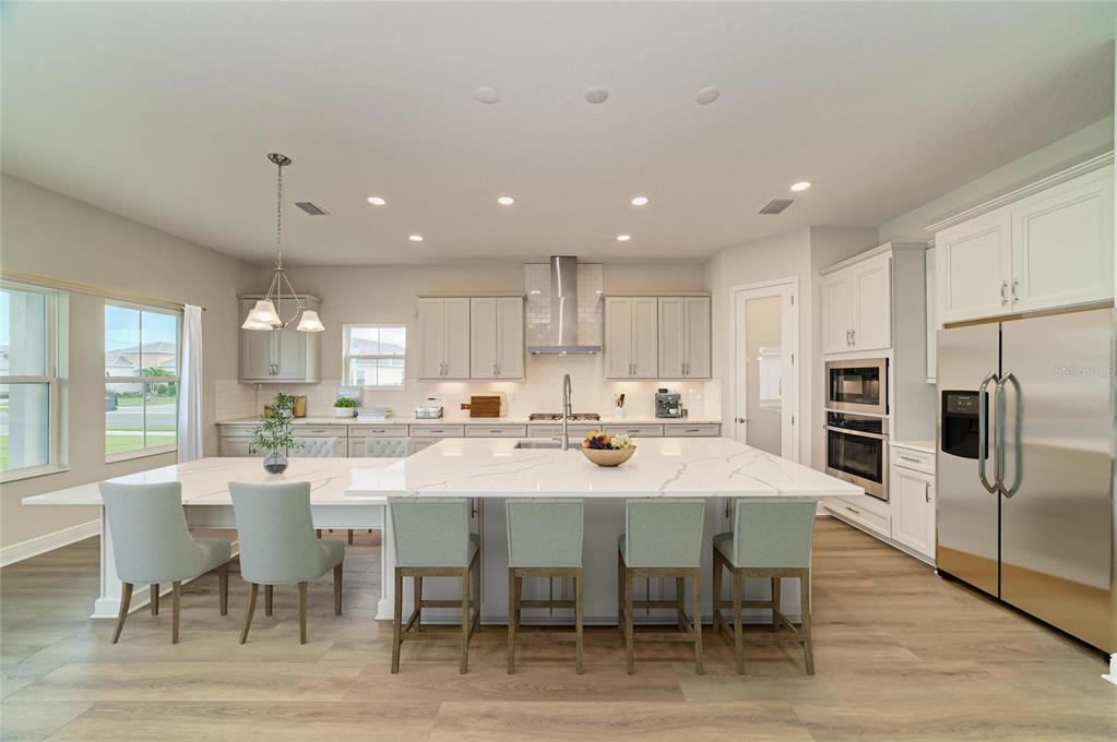 A modern kitchen features a large white quartz island, stainless steel appliances, and light cabinetry — 10245 CROSS RIVER TRAIL, PARRISH, FL