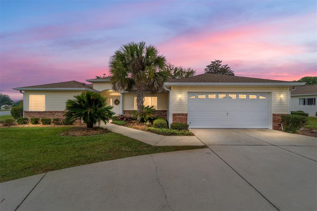 A single-story house with a beige exterior and a circular driveway sits on a corner lot — 13766 SE 89TH AVENUE, SUMMERFIELD, FL